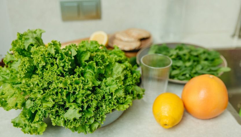 A vibrant display of fresh green lettuce and citrus fruits on a kitchen table.